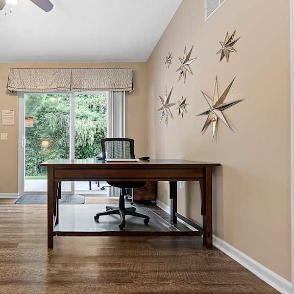 a room with a desk and a chair in front of a window.