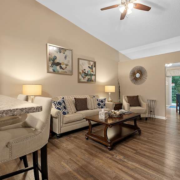 a living room with a white ceiling fan and a wooden floor.