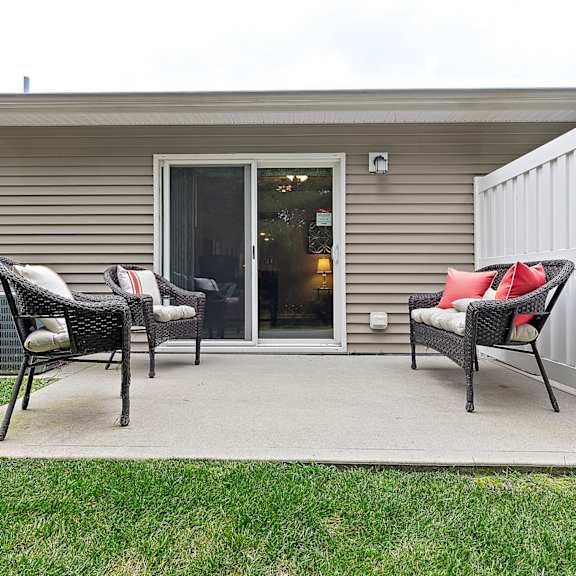 two chairs and a table are on a patio outside a house.