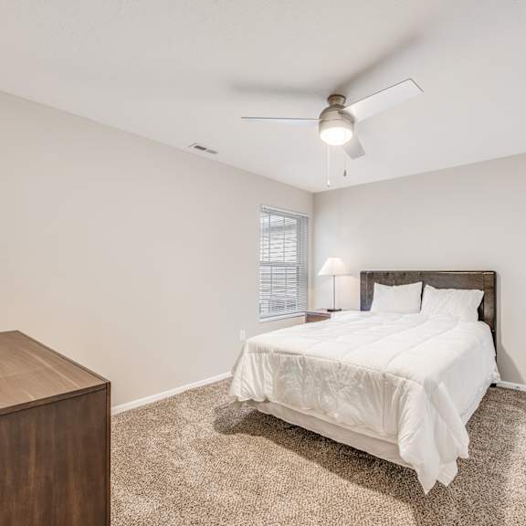 a bedroom with a bed, nightstand, and window.
