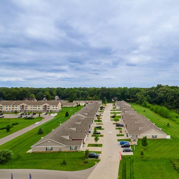 a row of houses with green lawns and trees in the background.