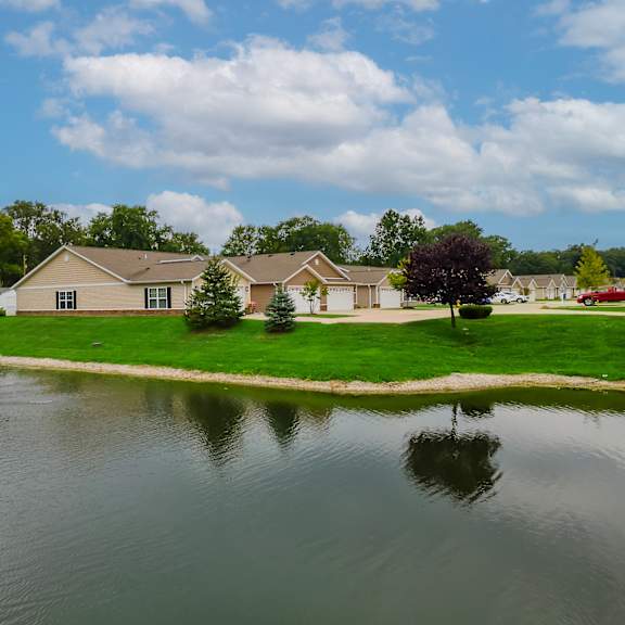 a fountain in the middle of a lake in front of a house.