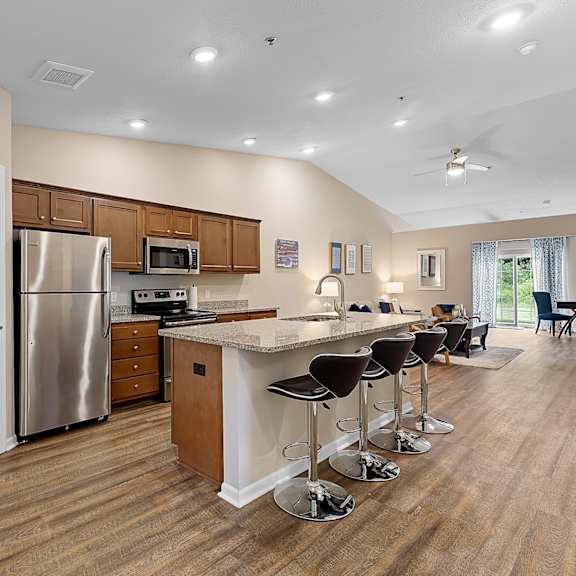 a kitchen with a refrigerator, stove, and bar stools.