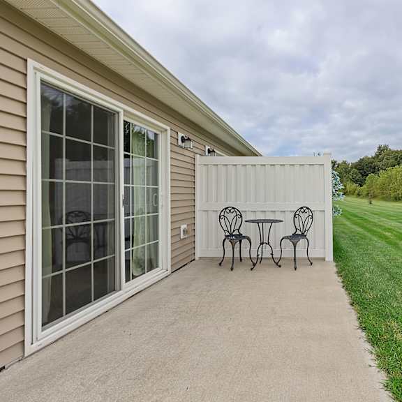a patio with a table and chairs is in front of a house.