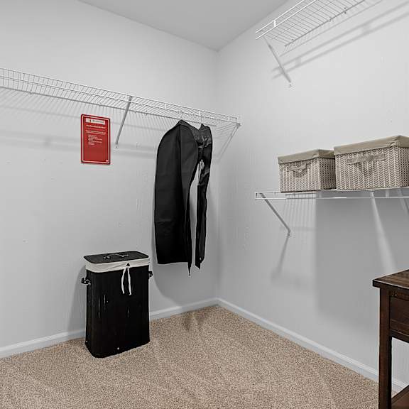a room with a coat hanging on a rack and a trash can.