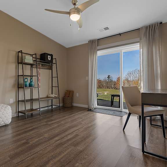a room with a ceiling fan and a desk with a chair.