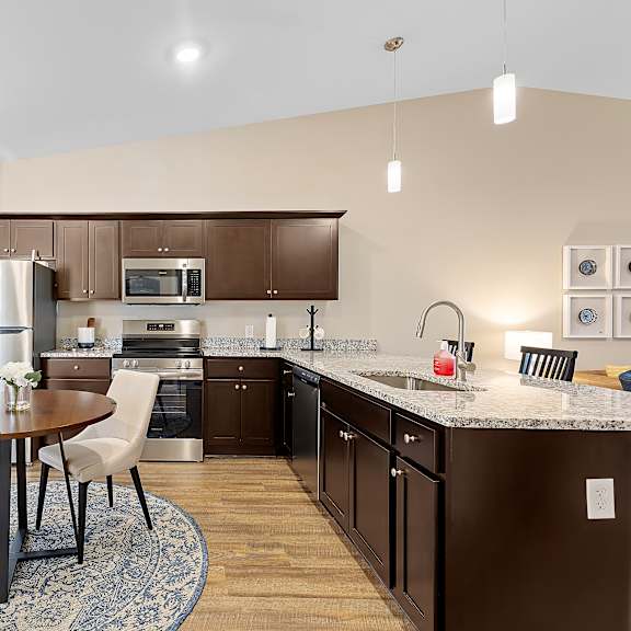 a kitchen with brown cabinets and a round table with four chairs.