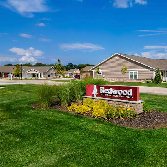 a redwood sign is in front of a building with a green lawn.