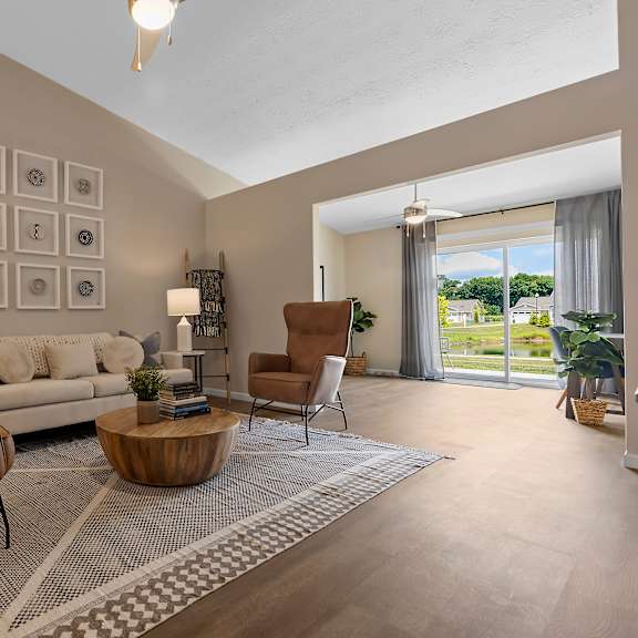 a living room with a grey sofa, a wooden coffee table, and a large window with a view of the outdoors.