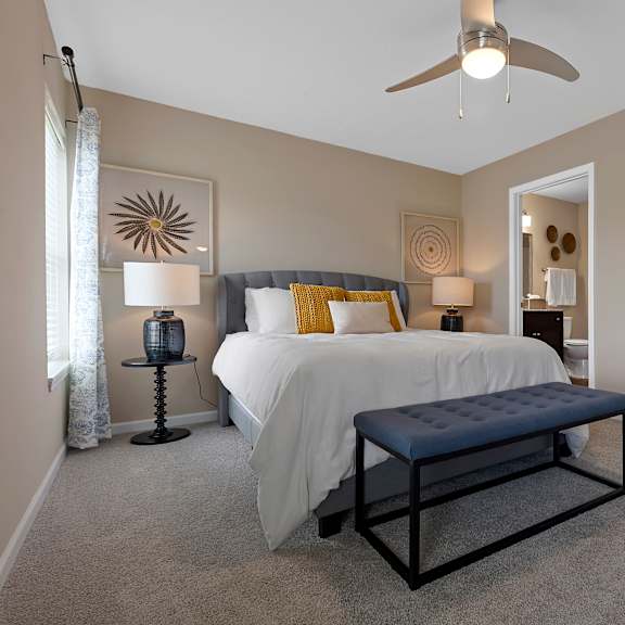 a bedroom with a bed, a bench, and a ceiling fan.