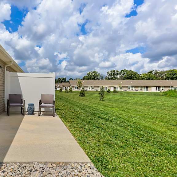 a patio with a chair and a table is in front of a house.