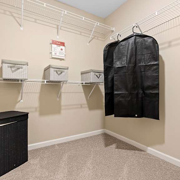 a walk-in closet with a hanging bag and shelves.