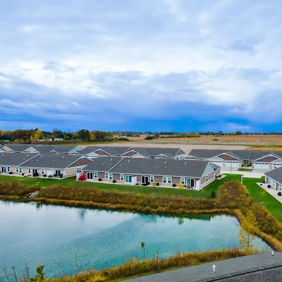 a row of houses with a pond in the foreground.