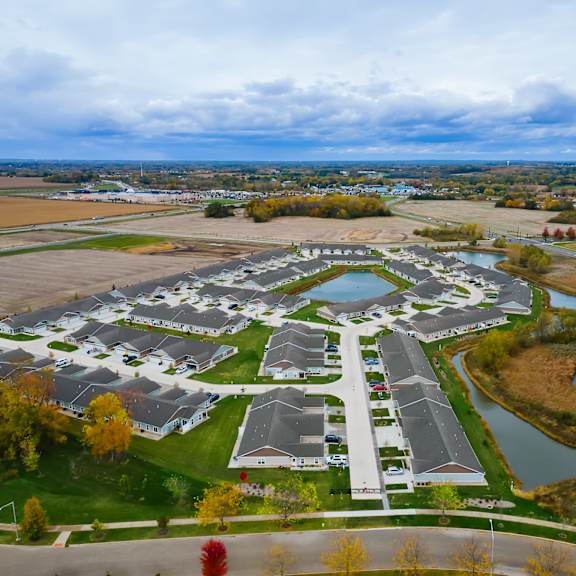a bird's eye view of a residential area with houses and a pond.