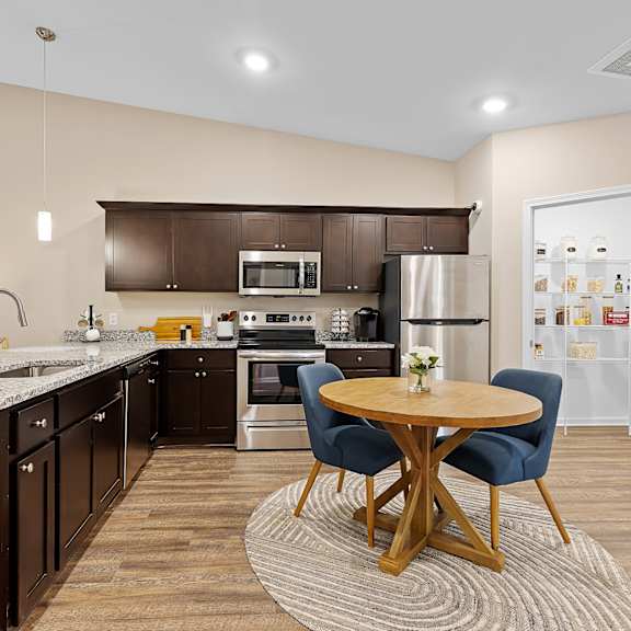 a modern kitchen with dark brown cabinets and a wooden table.