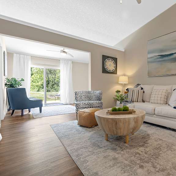 a living room with a white couch, a wooden coffee table, and a painting on the wall.