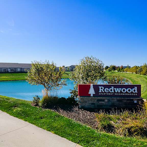 a sign for redwood apartment residences is in front of a building and a pool.