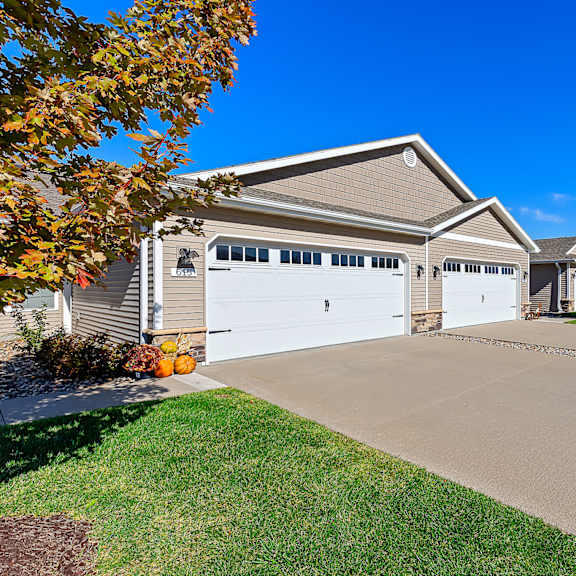 a house with a grey roof and two white garage doors.