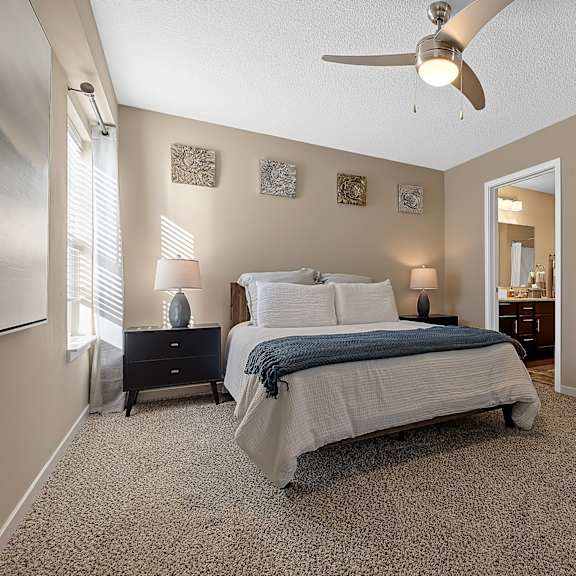 a bedroom with a bed, nightstand, and a ceiling fan.