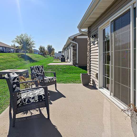 a patio with chairs and a table is in front of a house.
