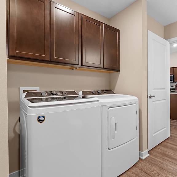 a white oven and dishwasher in a kitchen with brown cabinets.