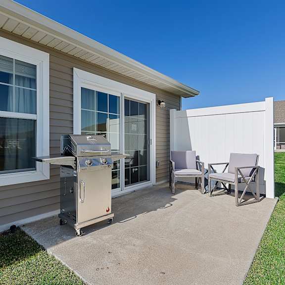 a patio with a grill and chairs.
