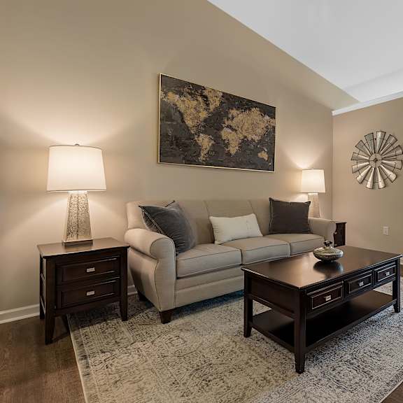 a living room with a beige couch, a coffee table, and a large painting on the wall.