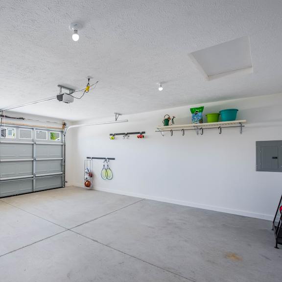 a garage with a grey door and a white wall.