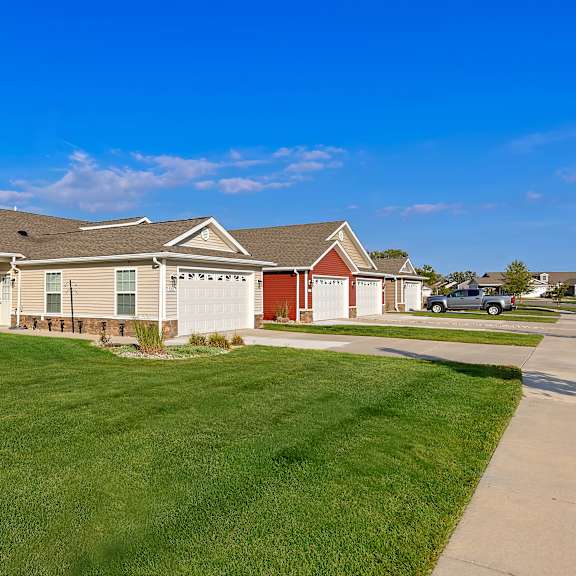 a house with a red garage door is surrounded by a well-kept lawn.