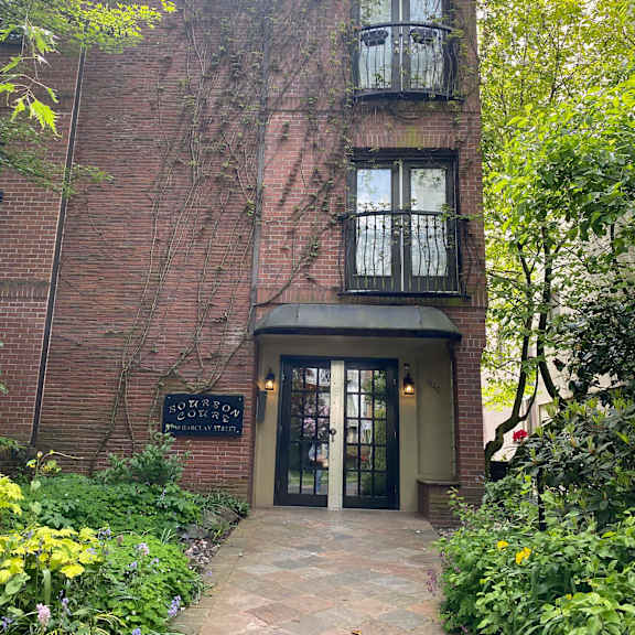 a red brick building with a large glass door and a black sign on the front of it