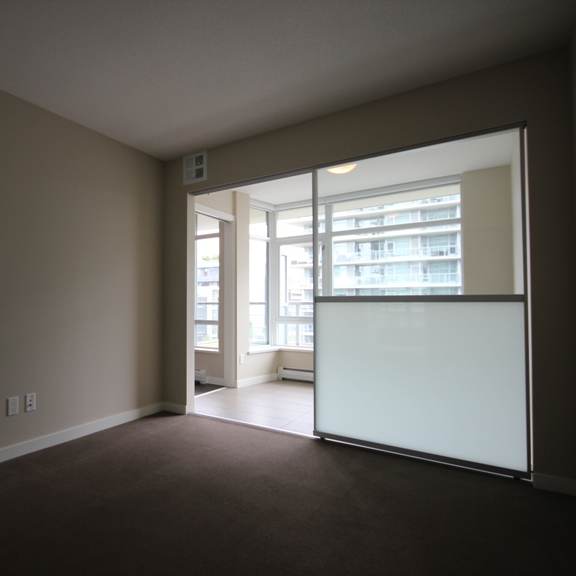 an empty living room with a sliding glass door leading to a balcony