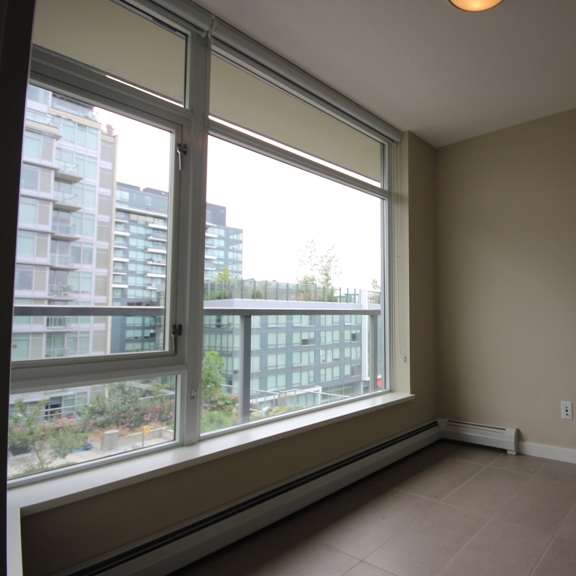 an empty room with a large window and tiled flooring