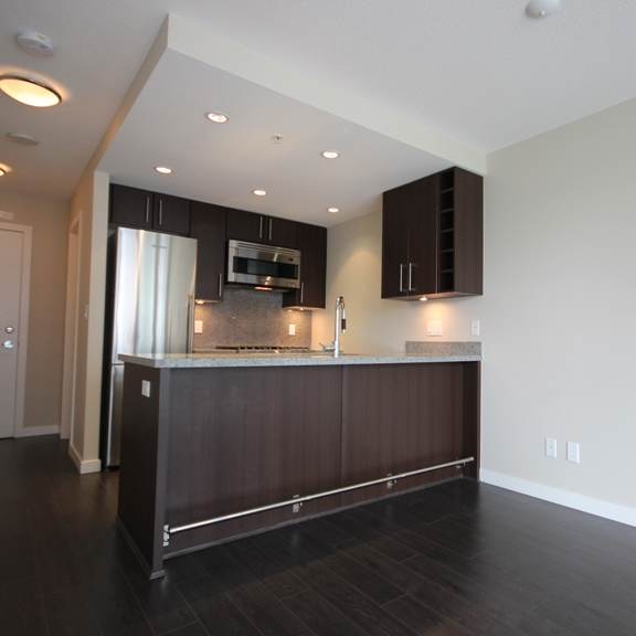 a kitchen with dark wood flooring and white walls