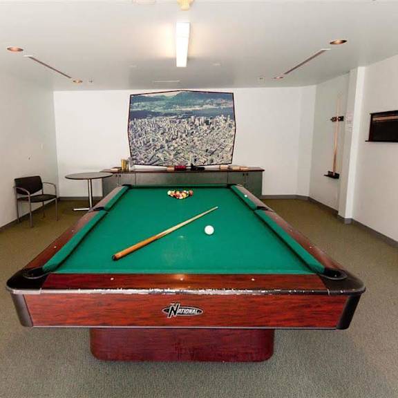 a pool table with green cloth and a white cue ball is in the middle of the room.