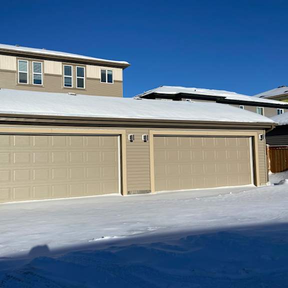 a row of garage doors in front of a house covered in snow.