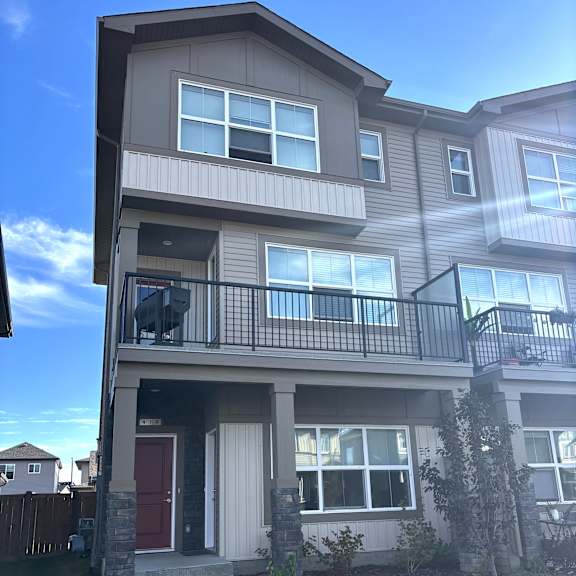 a two-story residential building with a red door and a balcony.
