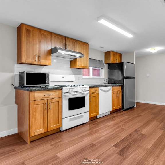 a kitchen with wooden cabinets and a black fridge.