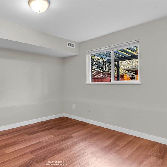 a room with wooden flooring and a window showing an outdoor view.