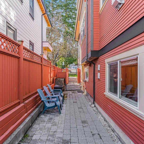 a red wooden fence with a bench and chairs on a patio.