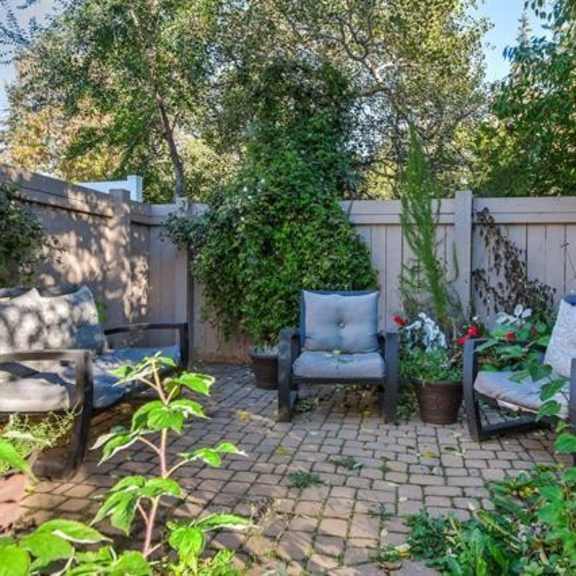 a backyard with a brick patio and two chairs.