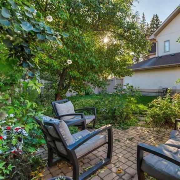 two chairs are placed on a patio in front of a house.
