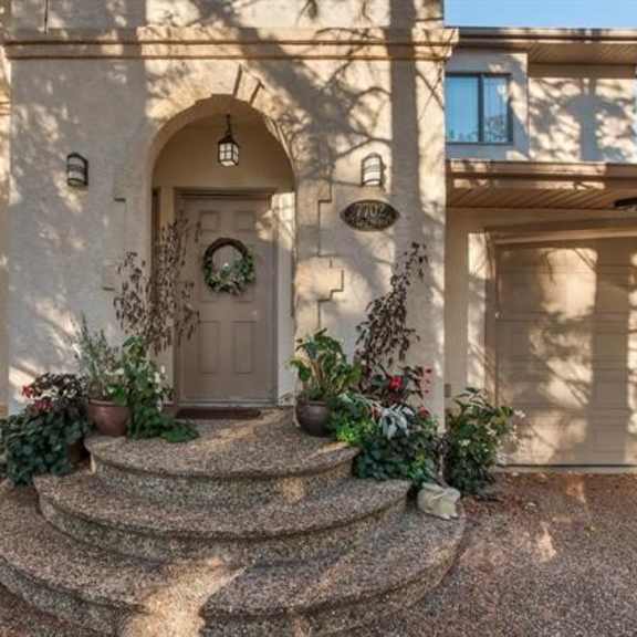a house entrance with a wreath on the door and plants on the steps.