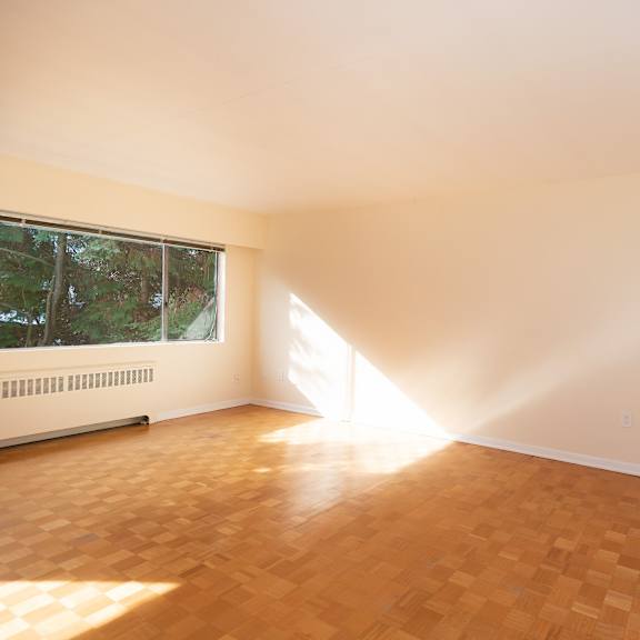 an empty room with a large window and a wooden floor