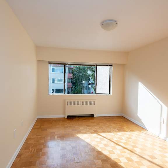 an empty room with a large window and a radiator