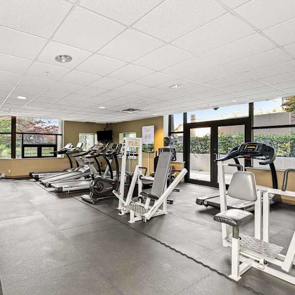 a gym with a variety of equipment including treadmills, weights, and exercise machines.