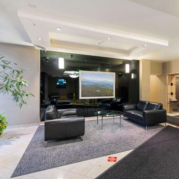 a modern living room with a large screen tv and black furniture.