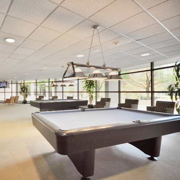 a large billiard table is in the middle of a room with a high ceiling and lots of windows.
