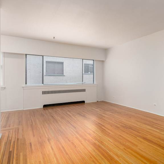 a bedroom with hardwood floors and white walls