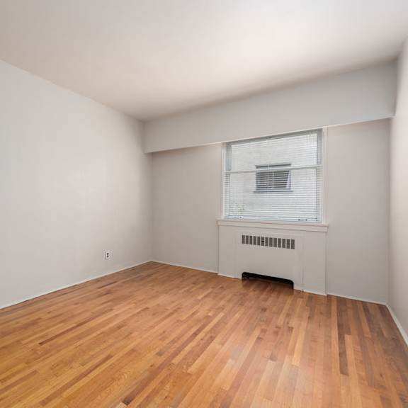 a bedroom with hardwood floors and white walls
