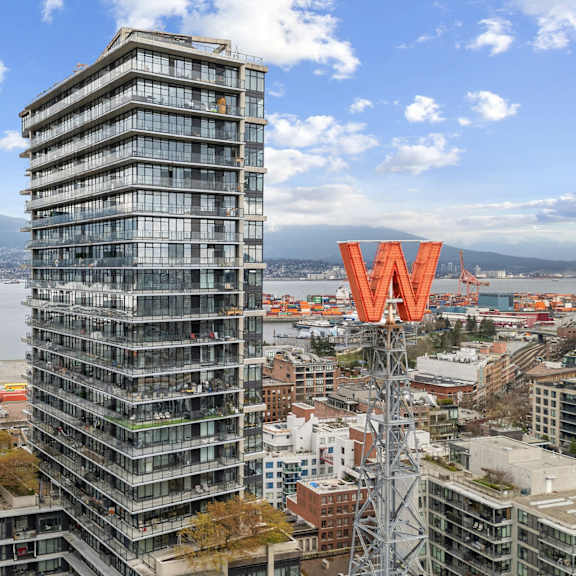a tall building with a w on top stands in front of a cityscape.